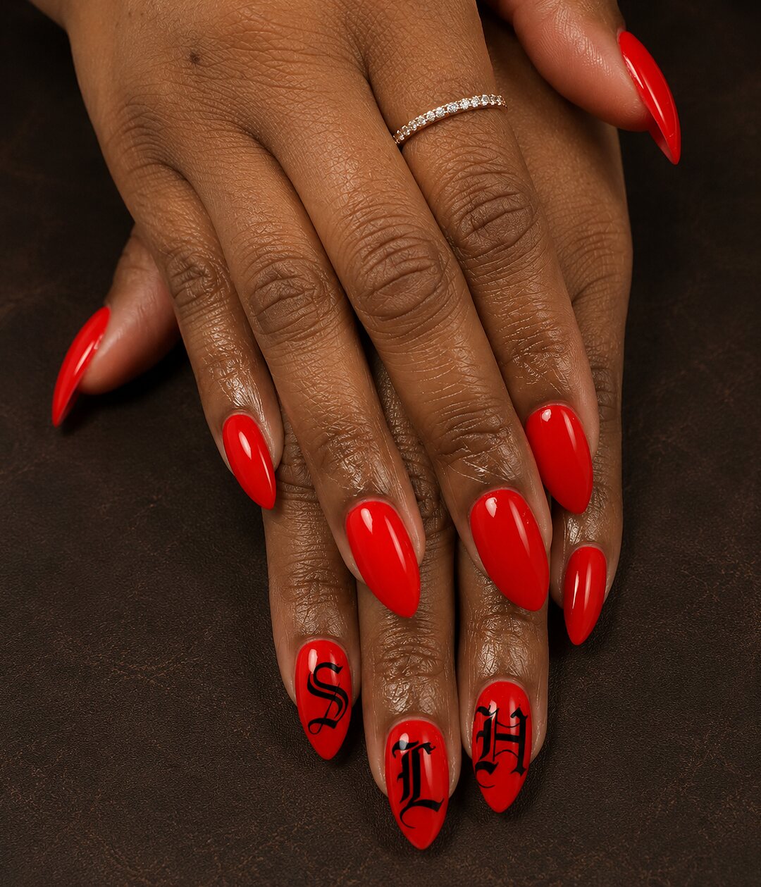 Long red stiletto nails with hand-painted black script detail
